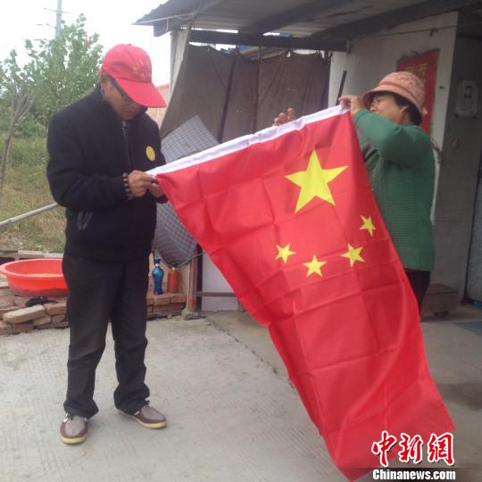 临近国庆,赵伦波老人换了一面新国旗,正在与老伴整理国旗。 刘林 摄