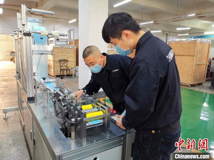 资料图：技术工人在对口罩机生产线进行最后调试。姜辉 摄